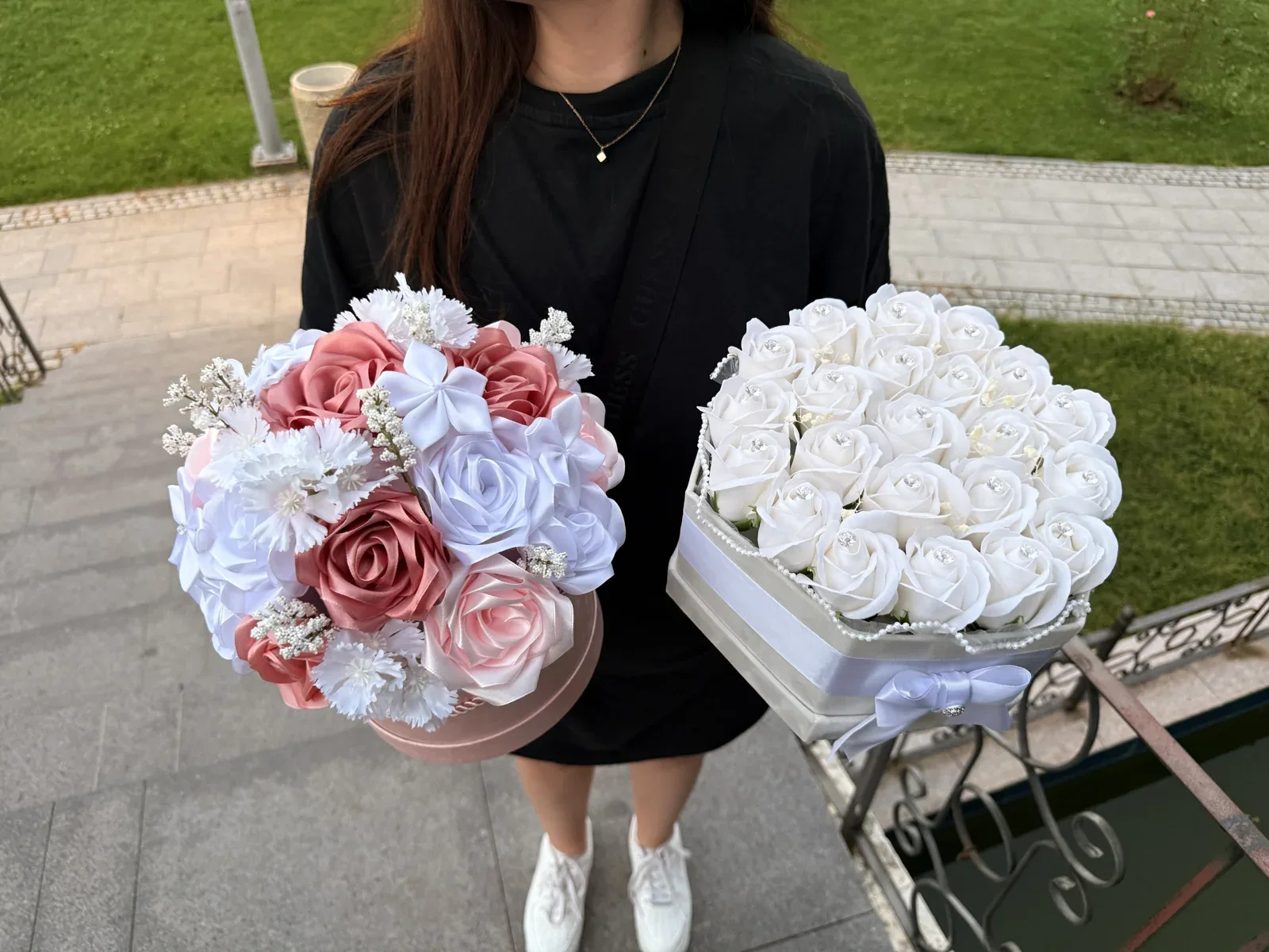 Două flower boxes VEV, cu flori albe și roz, prezentate în aer liber